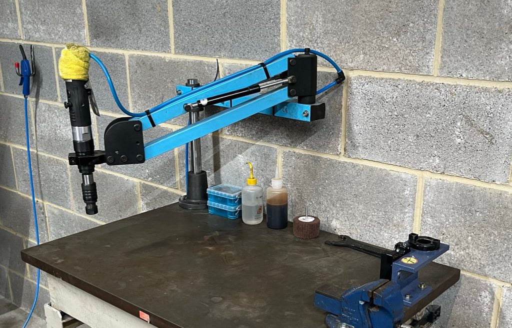 tapping arm on workbench with various attachments and grips